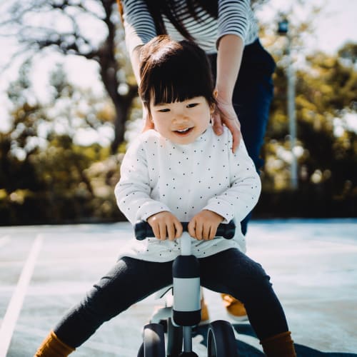 A mother helping her daughter ride a bike at Pacific View in Oceanside, California