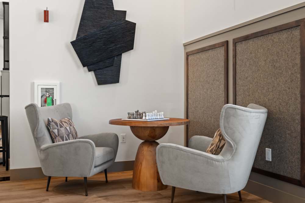 Two gray chairs and a table with black wall art at Broadstone Villas in Folsom, California