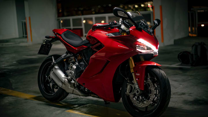 red motorcycle parked in a parking lot at night