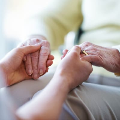Caregiver holding a memory care resident's hands compassionately at Cascade Park Gardens Memory Care in Tacoma, Washington