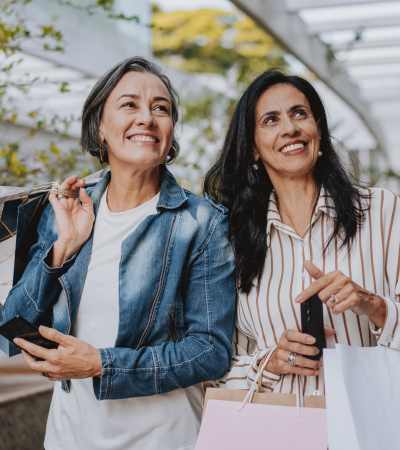 Two women smiling while holding shopping bags near Brush Factory Lofts in Philadelphia, Pennsylvania