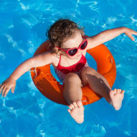 Child floating in an orange inner tube in a sparkling blue pool at 43 North Apartments in Grand Haven, Michigan