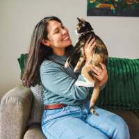 Woman holding cat on sofa at Cape At Savona Apartments in Cape Coral, Florida