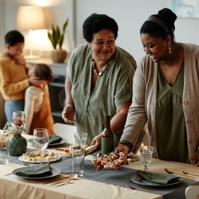 Two women setting a dinner table with children in the background at Walnut Creek Apartments in Macon, Georgia