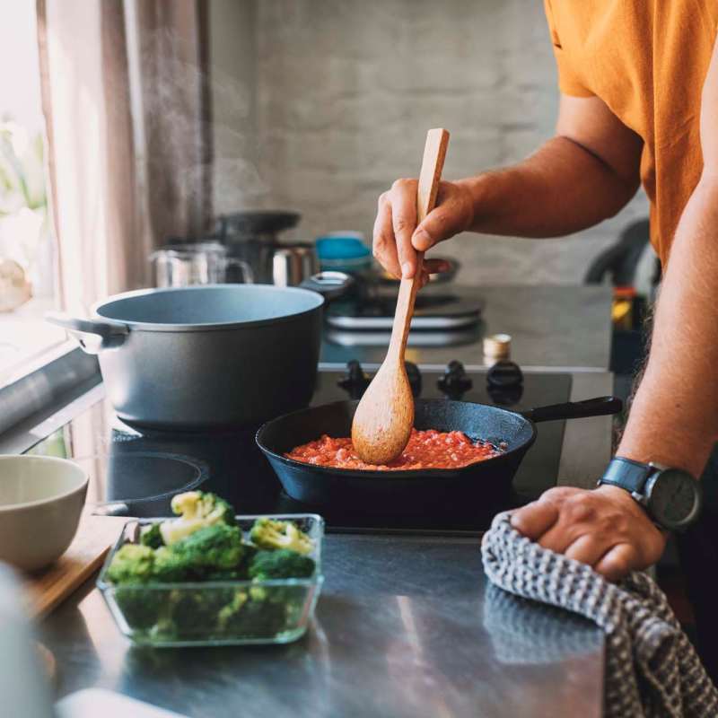 Resident cooking in kitchen at Waterstone Place Apartments in Stafford, Texas