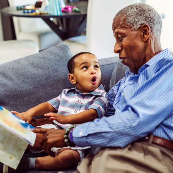 Resident reading book with little boy  at Brightwater Senior Living of Highland in Highland, California