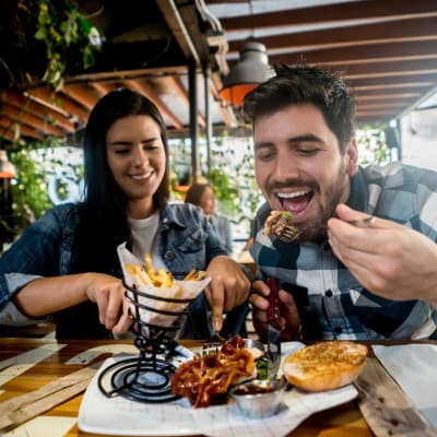 Friends enjoying a tasty burger at a bbq at Summerfield Apartment Homes in Harvey, Louisiana