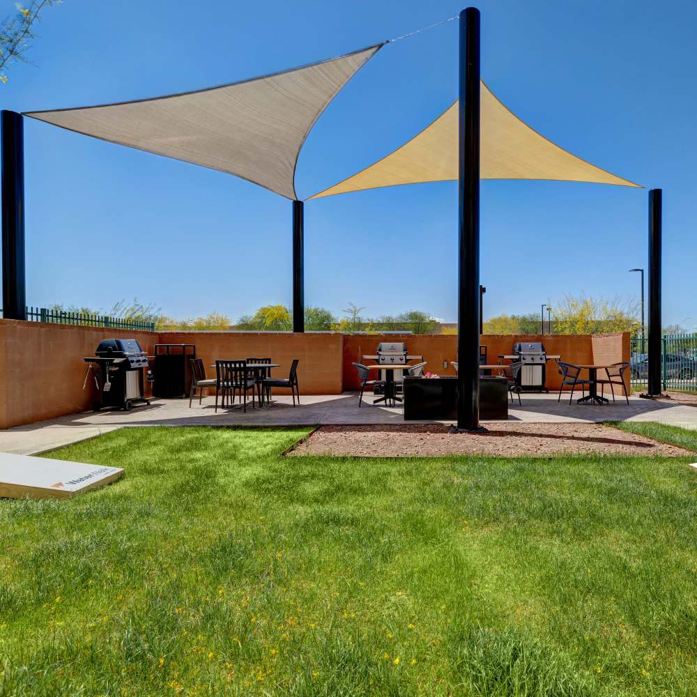 Outdoor grilling and seating area with triangular shade sails overhead at WaterWalk Phoenix - North Happy Valley in Phoenix, Arizona