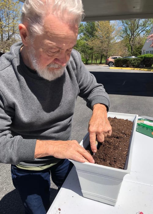 Resident adding soil to a planter box at Lavender Hills Front Royal Campus in Front Royal, Virginia
