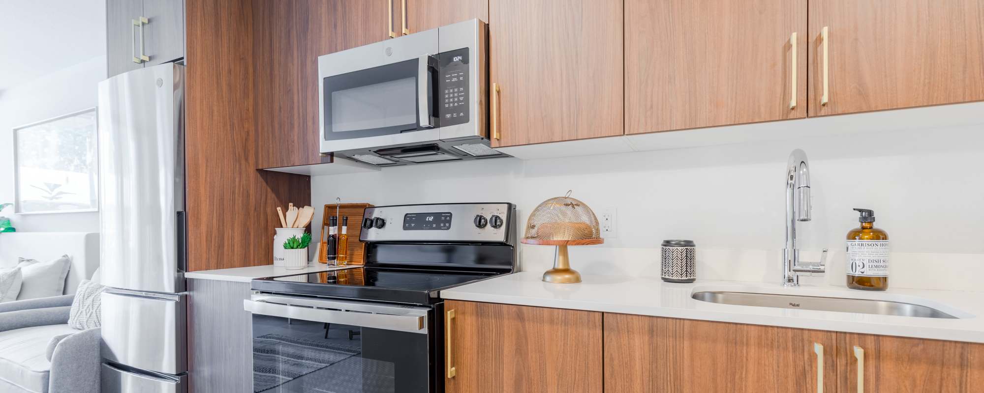 Kitchen with range, oven, marble countertop and wooden cabinetry at Alture Westland in Hialeah, Florida
