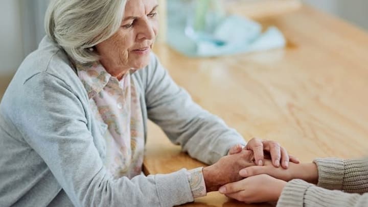 Senior woman holding hands with loved one after a discussion about senior care