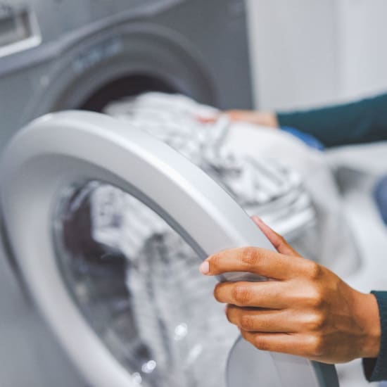 Resident doing laundry using her in-home washer and dryer at Eight Mile House in Stockton, California