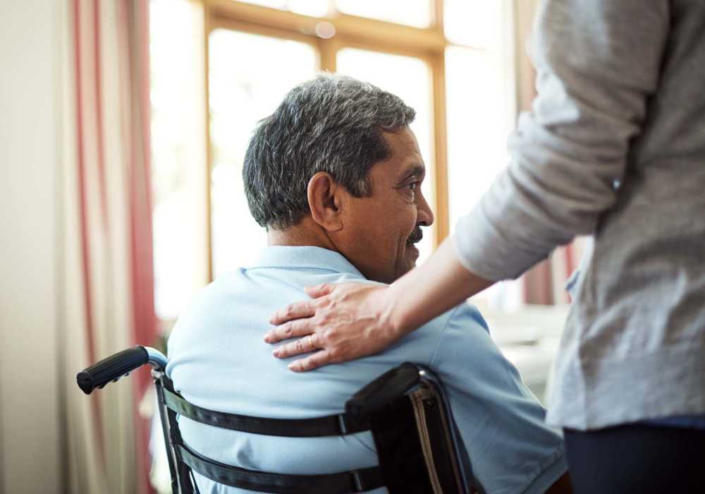 Man in a wheelchair receiving assistance at Clearwater Newport Beach in Newport Beach, California