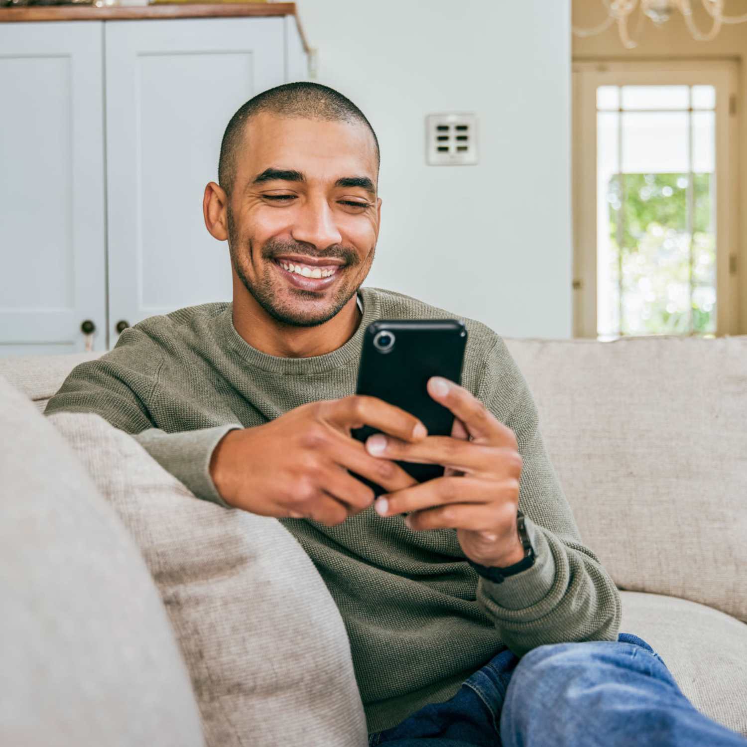 Resident looking at his phone while sitting on a couch at Forest Creek in Oklahoma City, Oklahoma