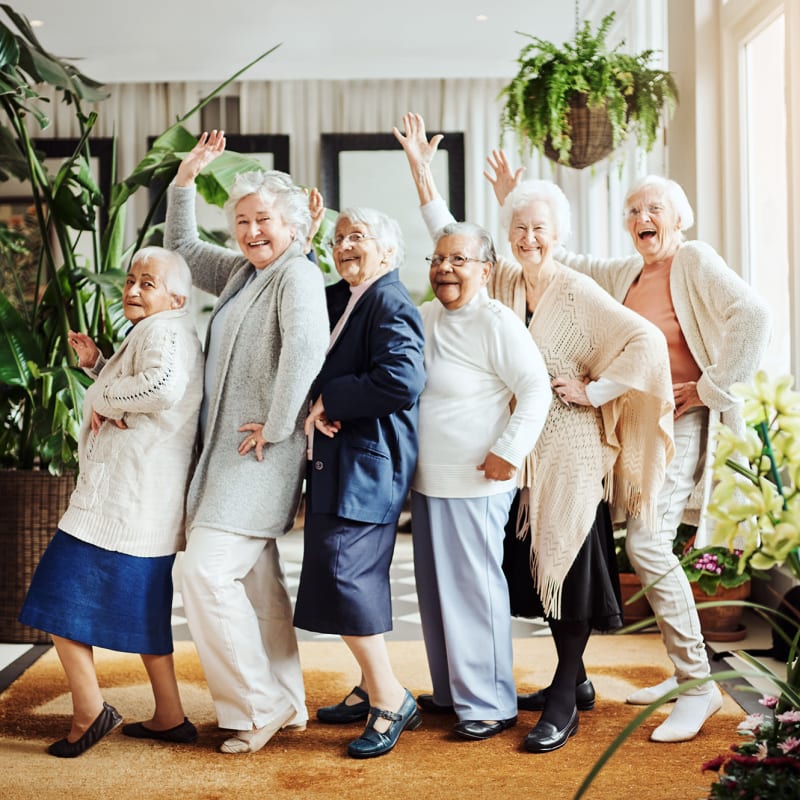 Residents standing in a line waving and smiling at the camera at Keepsake Village at Greenpoint in Liverpool, New York