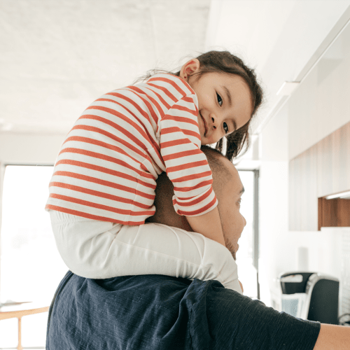 A resident with a child on his shoulders in their home at SOQ in Ridgecrest, California