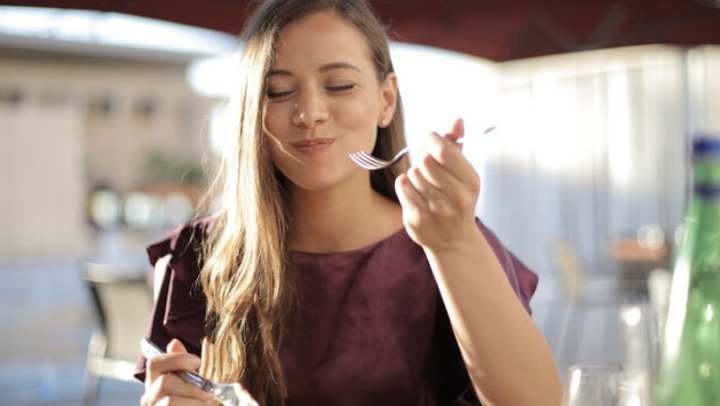 A woman enjoys a Mexican pizza near {{location_name}}, {{location_city}}, {{location_state_name}}