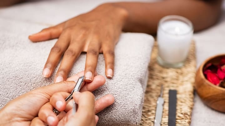 Close up of manicurist clipping client nails of a client. Her hand is resting on a grey towel. | Nail Salons in Chandler