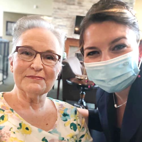 A masked team member with a resident at The Oxford Grand Assisted Living & Memory Care in McKinney, Texas