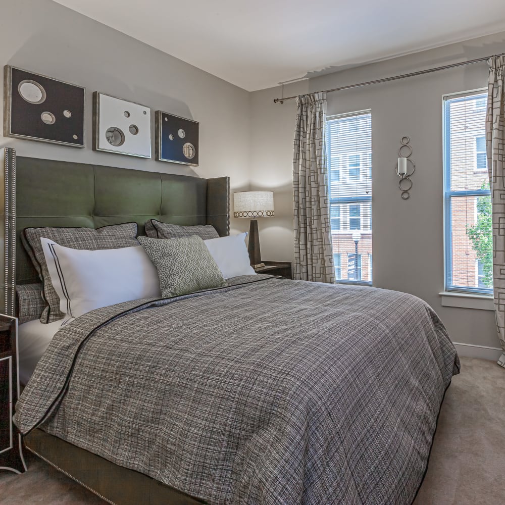 A bed by a window in an apartment bedroom at Mode at Hyattsville in Hyattsville, Maryland