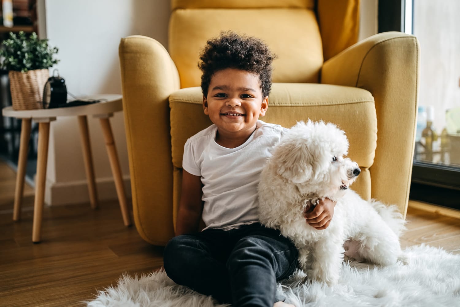 Little boy holding his dog while sitting on the floor at home at Post Ridge Apartments in Nashville, Tennessee