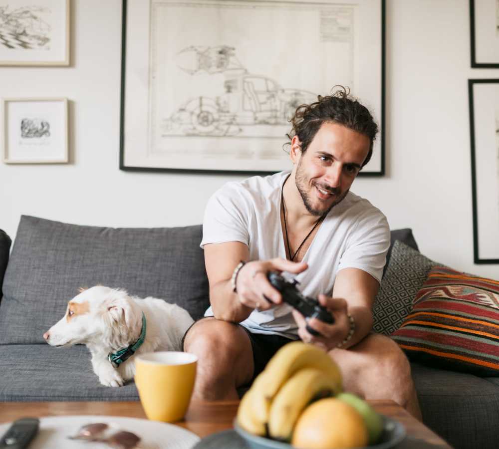 Student enjoying his game with his pet in the living room at The Edge in Pensacola, Florida