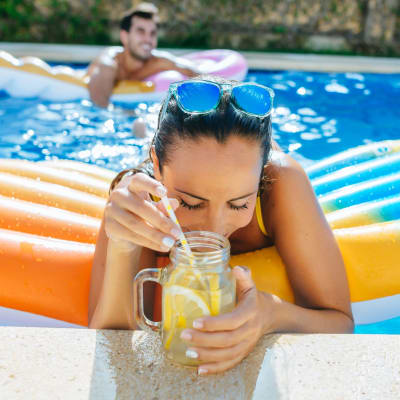 Woman enjoying a festive drink in the pool at The Oasis at Regal Oaks in Charlotte, North Carolina