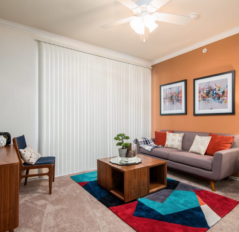 Retro-furnished living area with plush carpeting and a ceiling fan in a model home at Rockbrook Creek in Lewisville, Texas