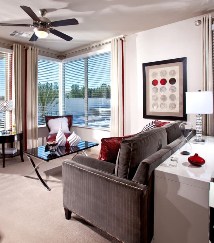 Well-furnished living area with large bay windows and plush carpeting in a model home at Sofi Warner Center in Woodland Hills, California