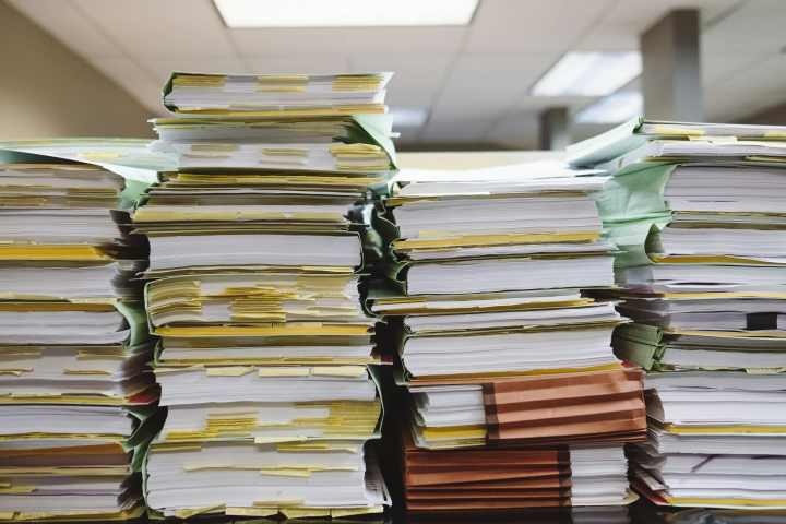 papers, files, and folders stacked on top of each other 8 or 9 high. 