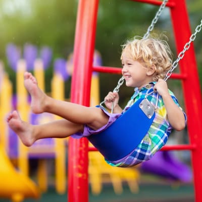 Kid swinging at a playground near Republic House at Frisco Bridges in Frisco, Texas