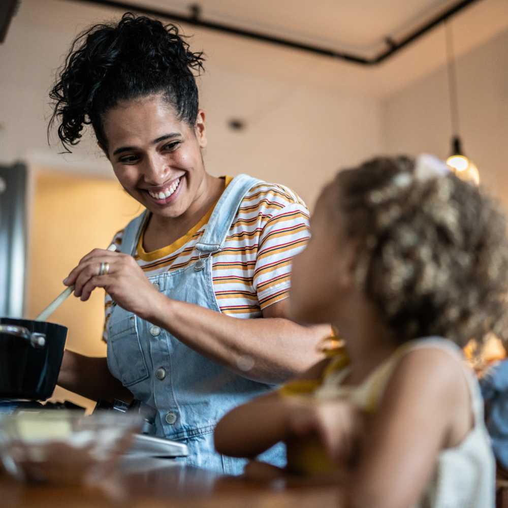 A woman and child engage in cooking activities in the kitchen at The Lido Apartments in Los Angeles, California