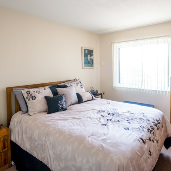 Model bedroom with light accents at Village Square Apartments in Williamsville, New York
