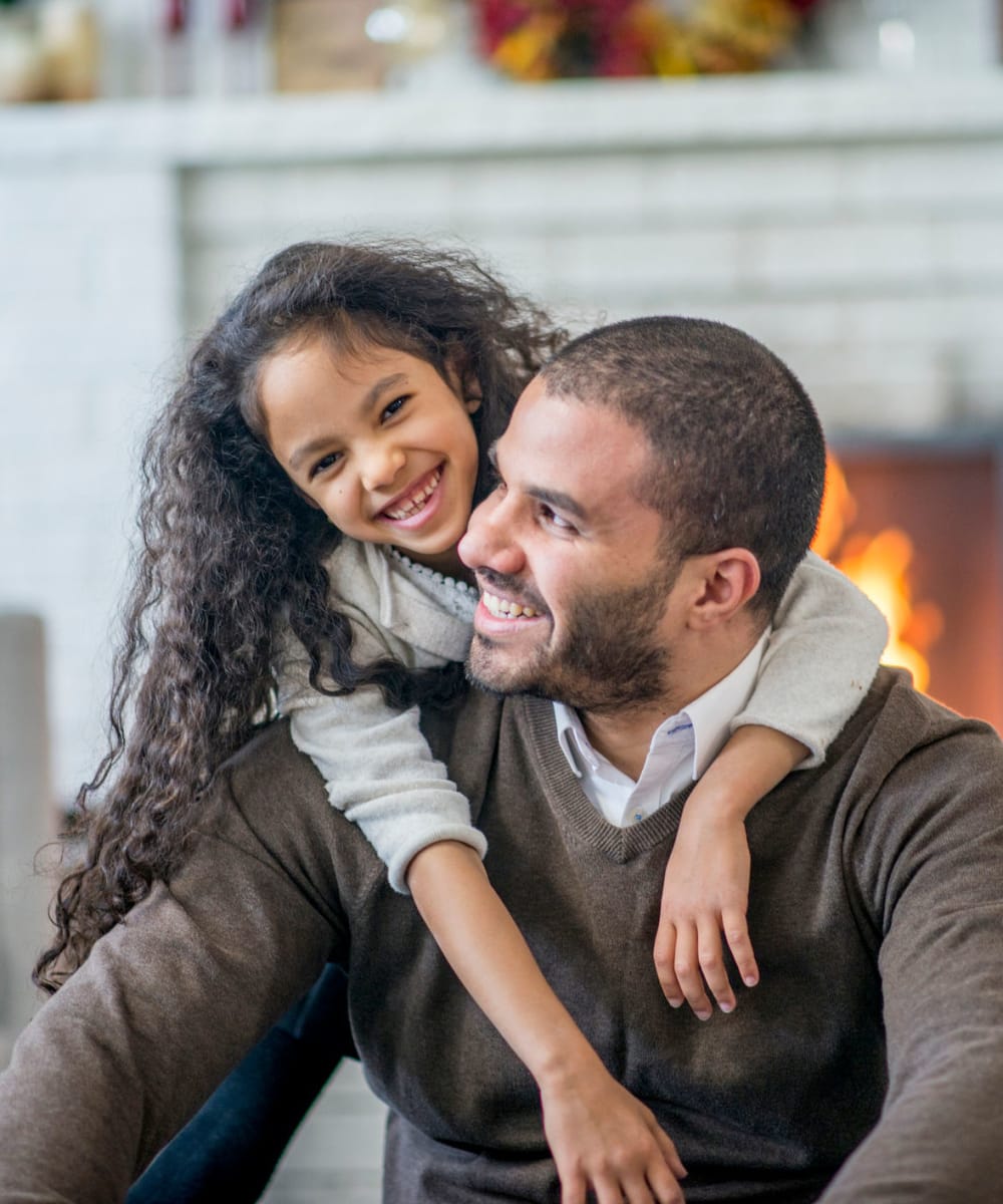 Father sitting by a nice fireplace with his child on his back at Big Sky Flats in Washington, District of Columbia