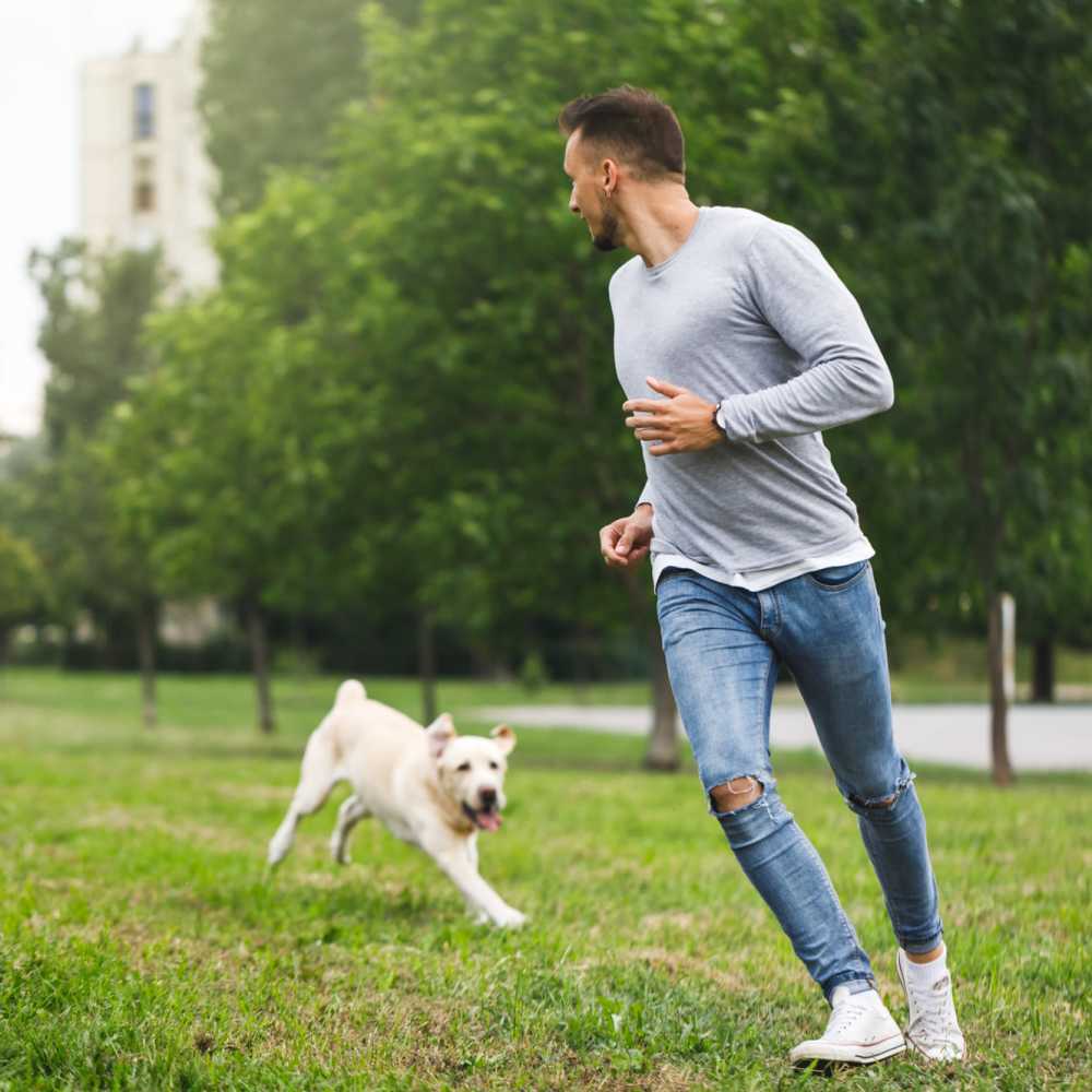 Resident playing with his dog in community on-site dog park at Covey Run Apartments in Forest Grove, Oregon