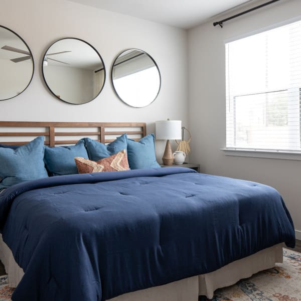 Apartment bedroom with 3 circular mirrors above the bed at Bellrock Memorial in Houston, Texas