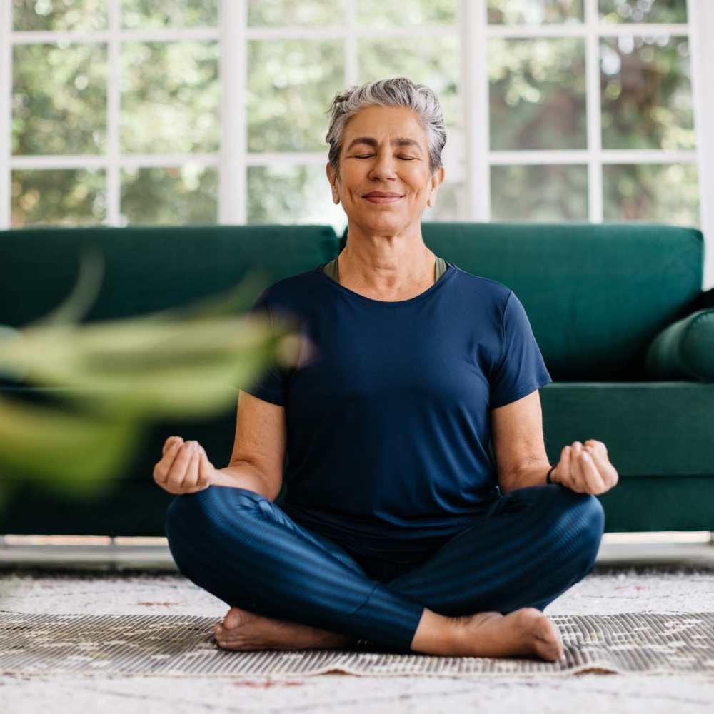 A happy meditating in her living room at The Manor At Union Crossing in Gastonia, North Carolina