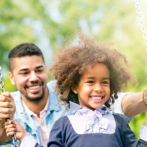 a man with his daughter on the swings near Pomerado Terrace in San Diego, California