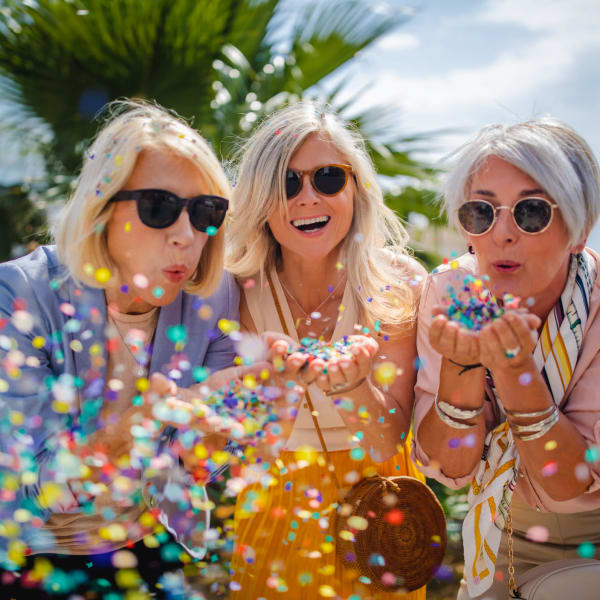 Women blowing confetti at Tampa Gardens Senior Living in Tampa, Florida