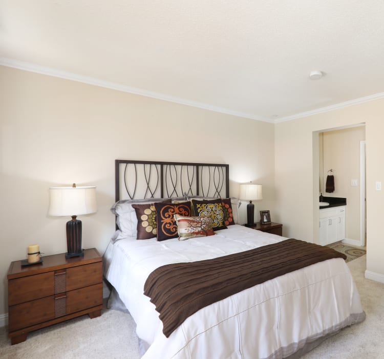 Master bedroom with plush carpeting and an en suite bathroom in a model home at Sofi Redwood Park in Redwood City, California