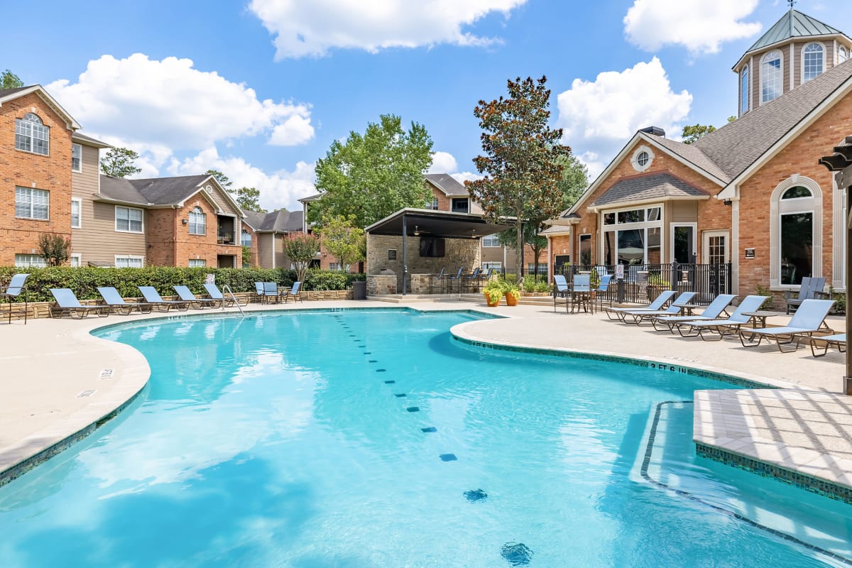 Sparkling pool with hot tub and turquoise lounge chairs at Marquis at Kingwood in Kingwood, Texas
