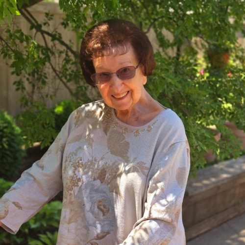 A resident smiling with a collection of flowers at Glen Carr House Memory Care in Derby, Kansas