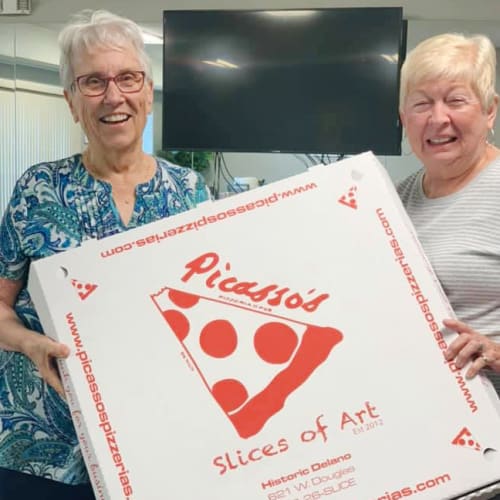 Residents holding pizza at Oxford Villa Active Senior Apartments in Wichita, Kansas