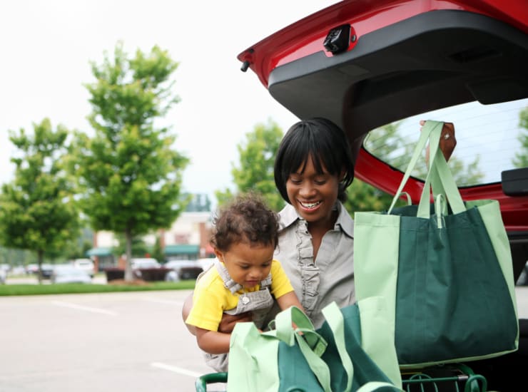 A mother holding her child while getting grocery bags out of her car at Woodside at Seven Pines in Jacksonville, Florida