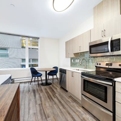 Spacious kitchen area with a dining table at the end with great wood flooring at Alley South Lake Union in Seattle, Washington