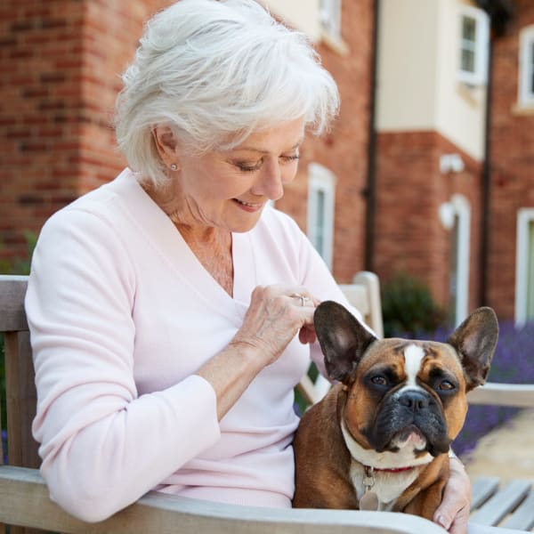 Senior woman sitting outside with her dog at Quail Park at Shannon Ranch in Visalia, California
