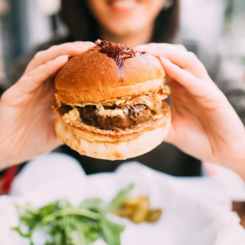 Woman eating her burger near 1221 Vallejo Apartments in Novato, California