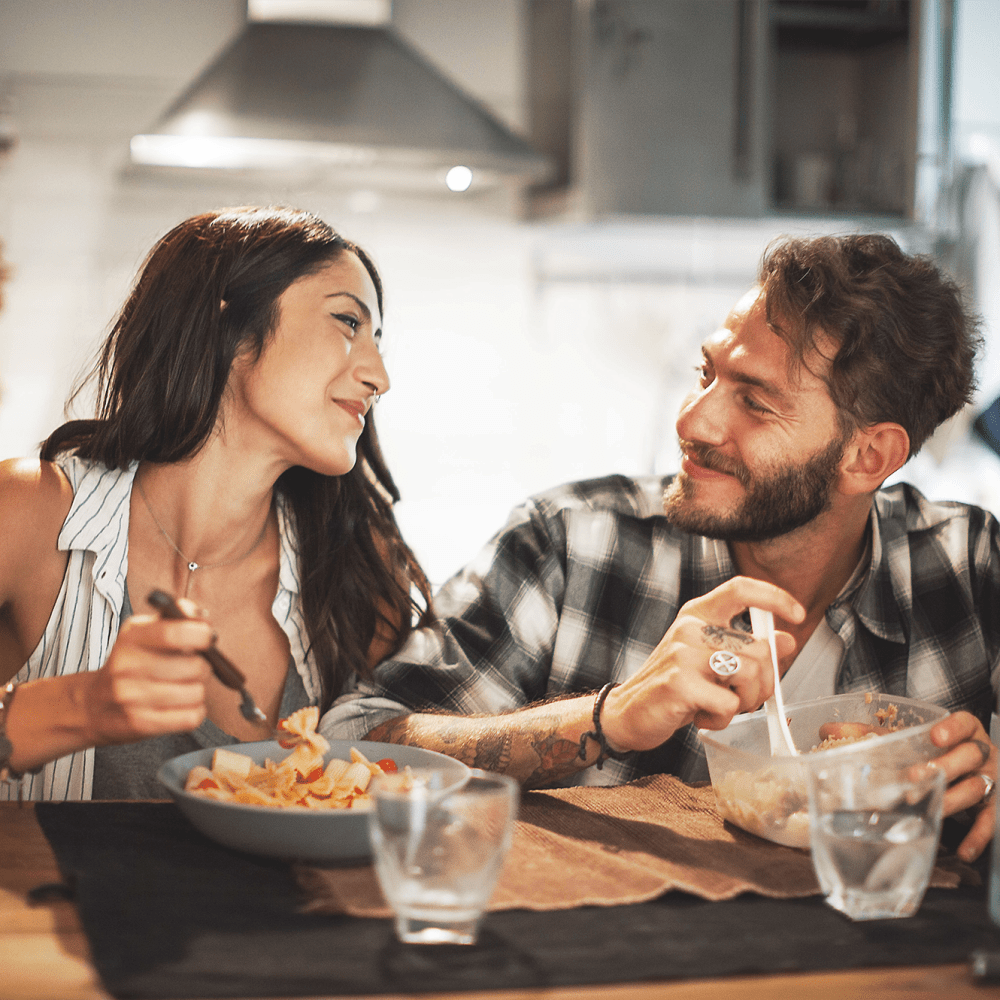 Resident couple smiling at each other while enjoying a meal in their new home's kitchen at our Rafael Gardens community at Mission Rock at Novato in Novato, California