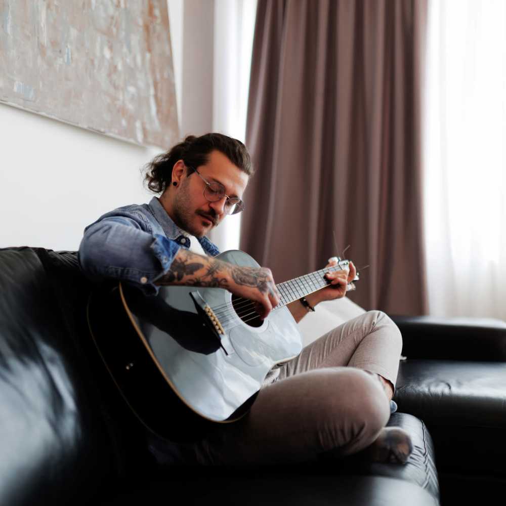 Resident playing guitar in his spacious living room at 10 Newbridge in Asheville, North Carolina