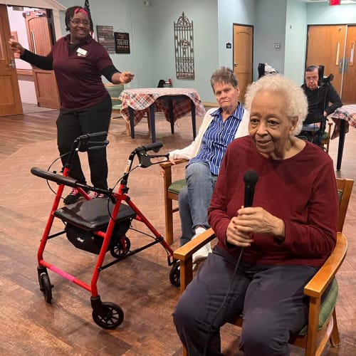 A resident tossing leaves outside at Oxford Glen Memory Care at Sachse in Sachse, Texas